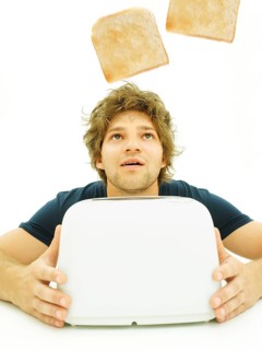 Young man looking at slices of toast as they pop out of a toaster