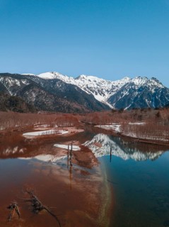 Snow-covered Japanese Alps reflected in Lake Taisho Pond