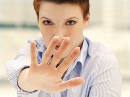 Businesswoman in an office making a defensive gesture with a raised hand