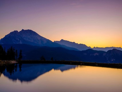 Mountain silhouettes reflected in an artificial mountain lake at sunset