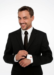 Man wearing a suit pulling an ace of hearts out of his sleeve