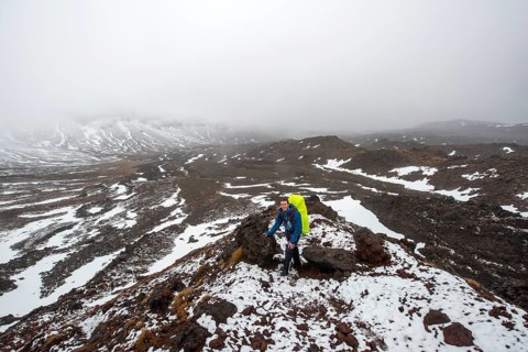 Hikers on hiking trail Tongariro Alpine Crossing in snow over lava fields