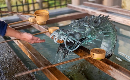 Ritual washing of hands at a sink with dragon figure at a Japanese temple