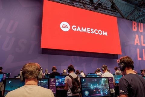 Visitors play video games under the gamescom logo at gamescom