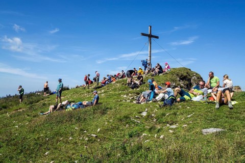 Mountain hikers rest at the summit cross of the Hoher Ifen mountain