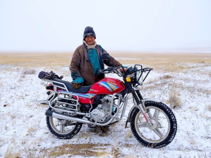 Old man with his motorcycle in a blizzard