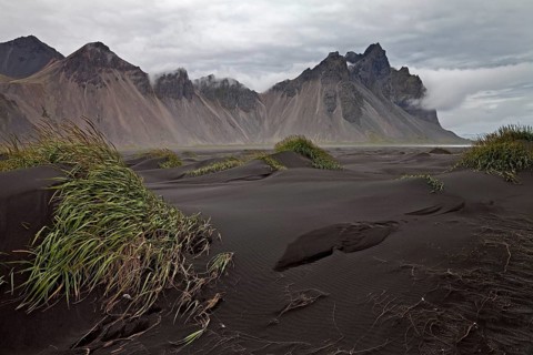 Black lava beach with dunes at Cape Stokksnes with mountain Vestrahorn