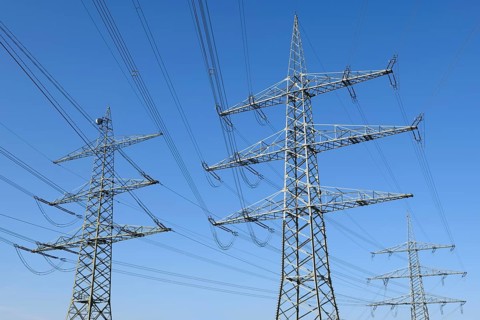 High-voltage pylons in front of a blue sky