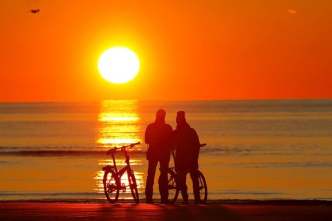 Couples with bikes on the beach watching the sunset