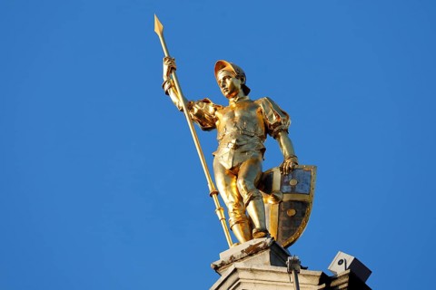 Golden figure with lance on gable of a guild house