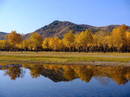 Autumn-coloured trees are reflected in the Tuul River at the entrance to Gorchi Terelj National Park
