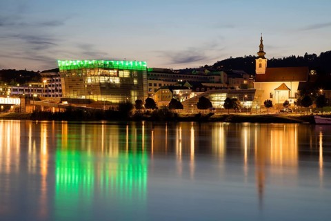 Danube bank with Ars Electronica Center at dusk