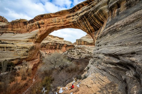 Tourist sits under rock arch