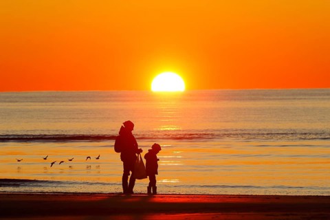 Mother and child on the beach at sunset