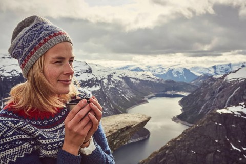 Young woman in Norwegian sweater drinks tea