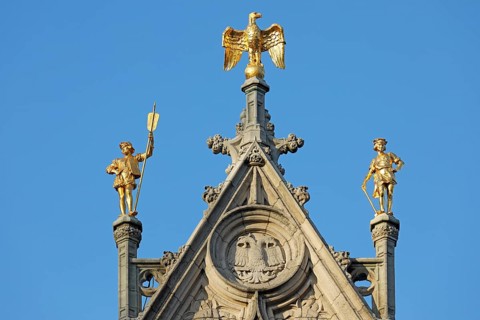 Golden figures with eagle figure on gable of a guild house