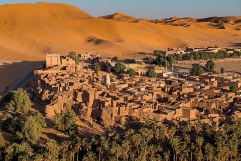 Overlook over the oasis of Taghit with sand dunes