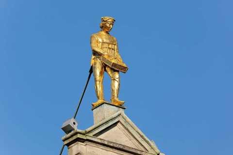 Golden figure on the gable of a guild house