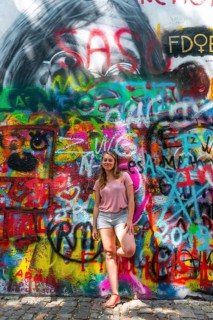 Woman standing in front of colorful graffiti at the John-Lennon-Wall