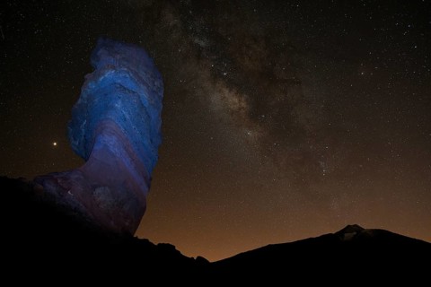 Illuminated Roque Cinchado and Pico del Teide with starry sky