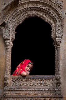 Young girl looking out of a window from an old haveli