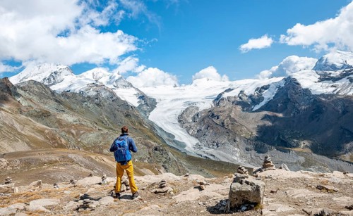 Hiker looks from the mountain Unterrothorn onto the glacier tongue of the Findel Glacier