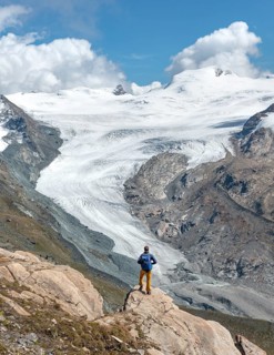 Hiker looks from the mountain Unterrothorn onto the glacier tongue of the Findel Glacier