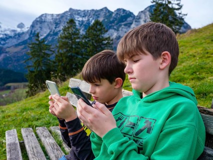 Two boys in nature are immersed in their smartphone