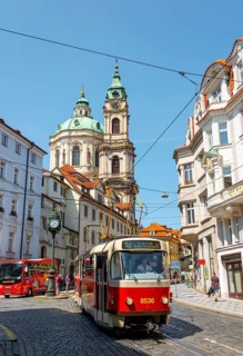 Red tram runs through a street