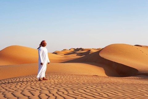 Bedouin in traditional clothing stands in the sand desert