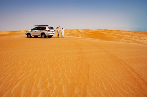 Tourist and Bedouin standing next to off-road vehicle