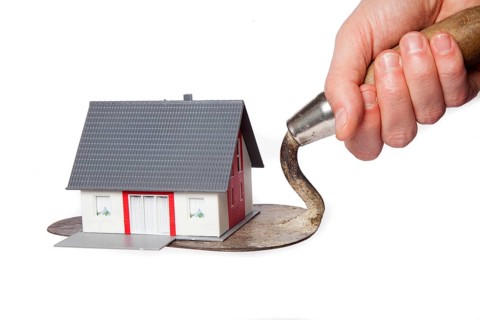 Toy model house on a trowel