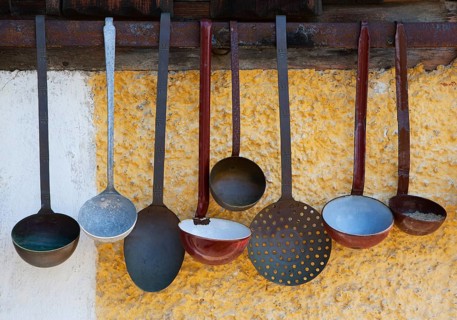 Various ladles hanging on a wall of a farm