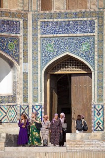 Women in traditional clothing in front of the entrance portal of the Mir-Arab-Madrasa