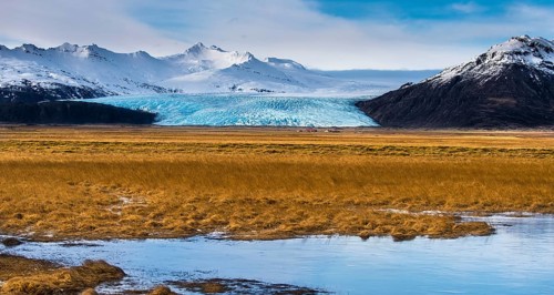 Icelandic farmstead with glacier tongue and snow-covered mountains