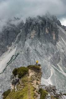 Woman in yellow jacket standing on a ridge