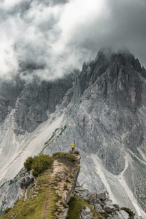 Woman in yellow jacket standing on a ridge