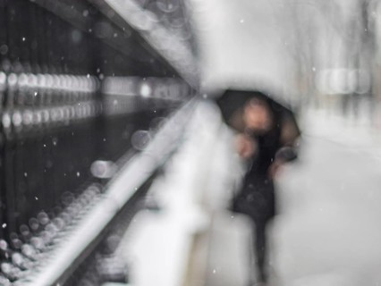 Woman with umbrella walking along a grating