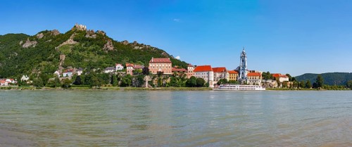 Excursion boat on the Danube in front of the baroque church of Duernstein Abbey