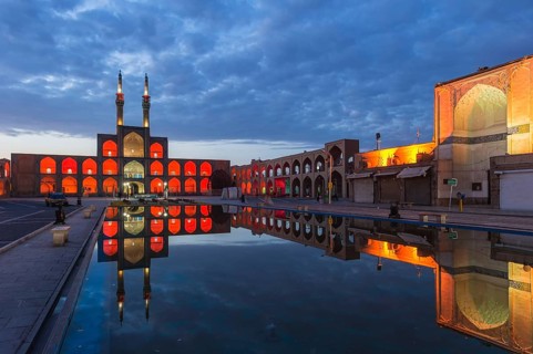 Amir Chaqmaq complex facade illuminated at sunrise and reflecting in a pond