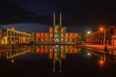 Amir Chaqmaq complex facade illuminated at sunrise and reflecting in a pond