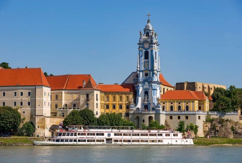 Excursion boat on the Danube in front of the baroque church of the monastery Duernstein