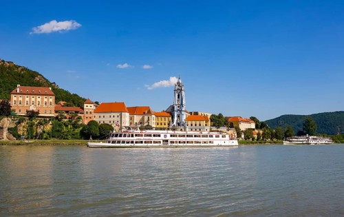 Excursion boat on the Danube in front of the baroque church of the monastery Duernstein