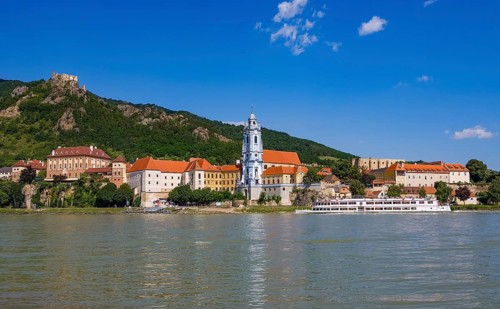 Excursion boat on the Danube in front of the baroque church of Duernstein Abbey