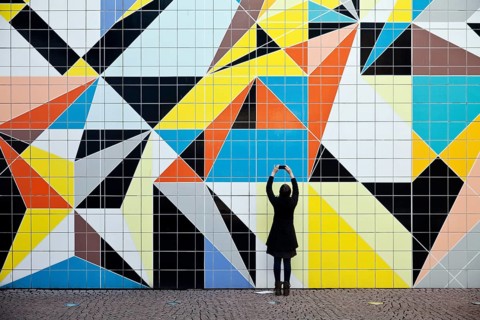 A woman photographs the mural Hornet
