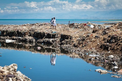 Girls on a huge mountain of rubbish on the coast