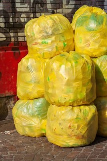 Stacked yellow bags for plastic waste in front of a house wall