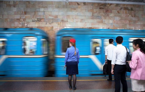 Conductor in uniform and passengers waiting at the passing train