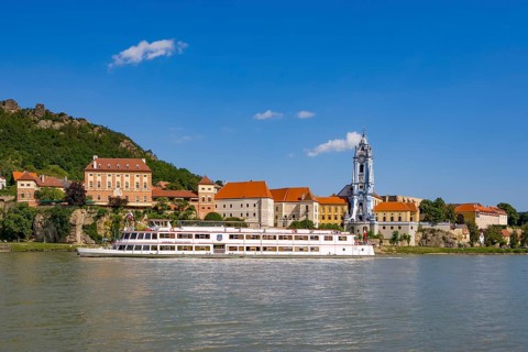 Excursion boat on the Danube in front of the baroque church of the monastery Duernstein