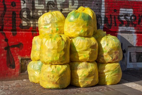 Stacked yellow bags for plastic waste in front of a house wall
